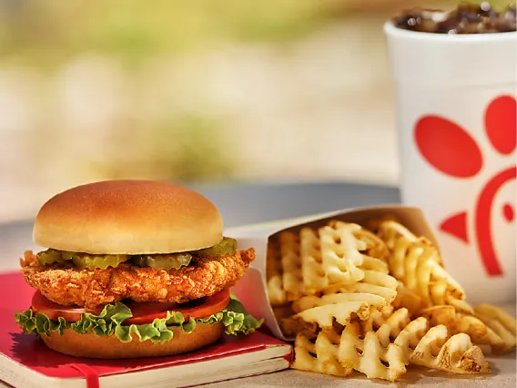 Chick-Fil-a Chicken Sandwich over a red notebook served with some fries and a soda