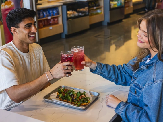 Image of boy on the left sitting across from a girl cheering at cafe bolo