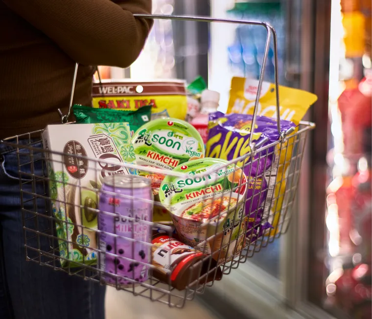 Zoomed in photo of person carrying a shopping basket full of international snacks